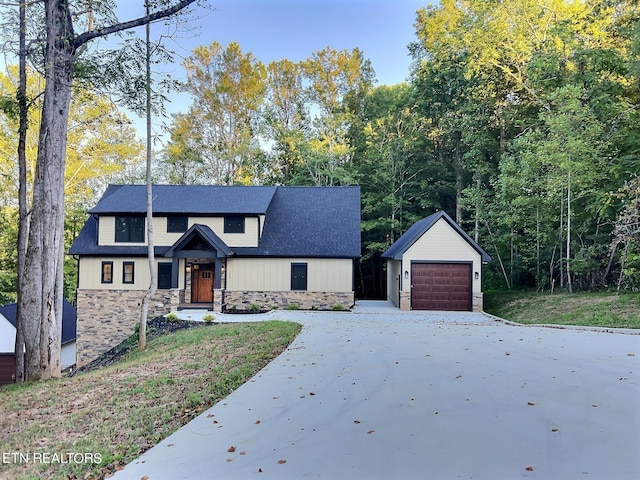 modern farmhouse featuring an outdoor structure, stone siding, concrete driveway, and a garage