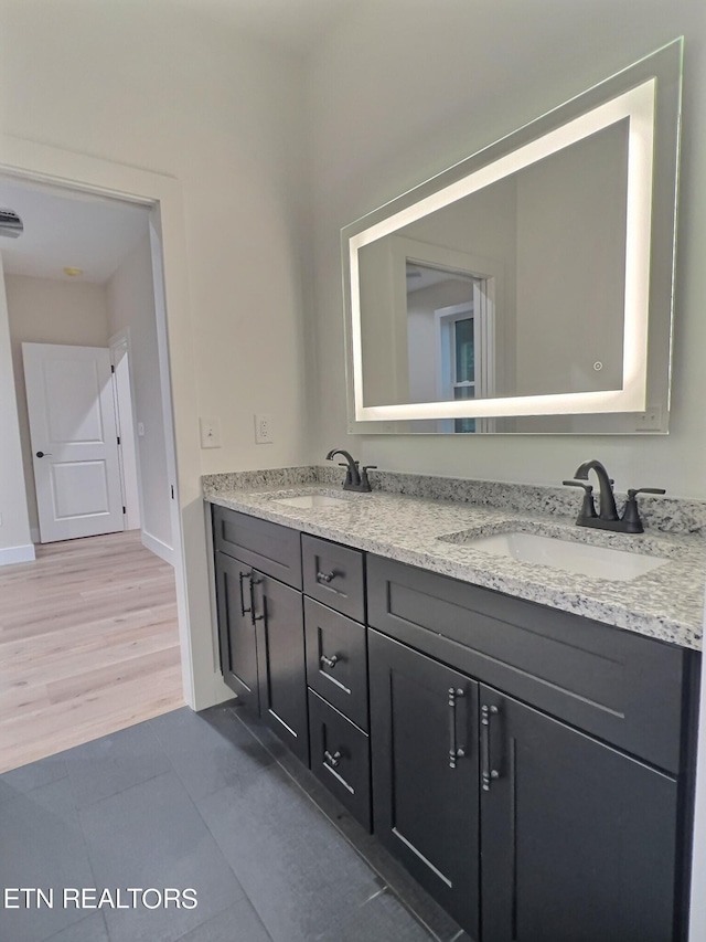 full bathroom with double vanity, wood finished floors, baseboards, and a sink