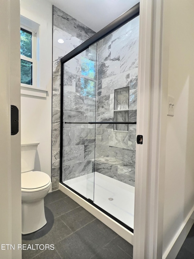 bathroom featuring toilet, an enclosed shower, and tile patterned floors