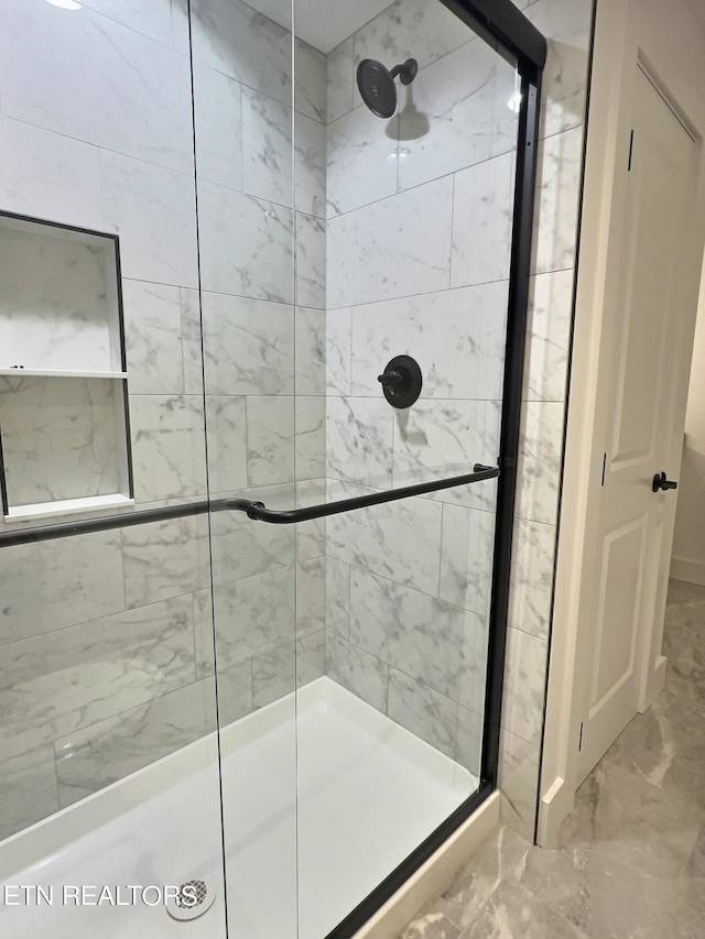bathroom featuring marble finish floor and a shower stall