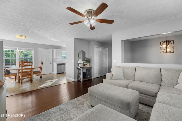 living room with a textured ceiling, light hardwood / wood-style flooring, and ceiling fan with notable chandelier