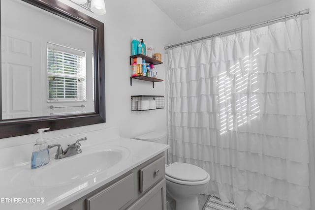 bathroom with a textured ceiling, vanity, toilet, and walk in shower