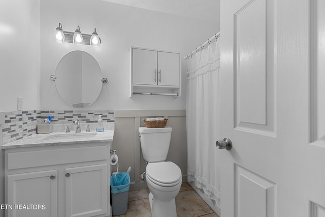 bathroom featuring toilet, tile patterned floors, vanity, curtained shower, and decorative backsplash