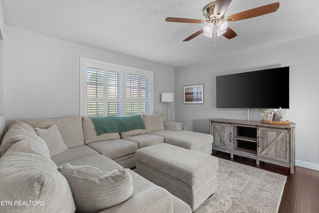 living room featuring dark hardwood / wood-style flooring, ceiling fan, and a textured ceiling