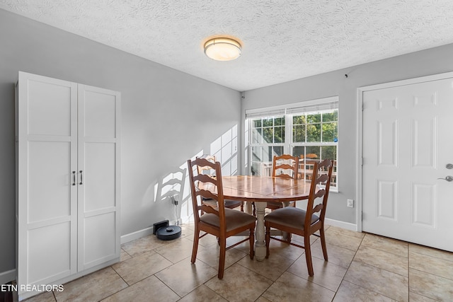 dining space with a textured ceiling and light tile patterned floors