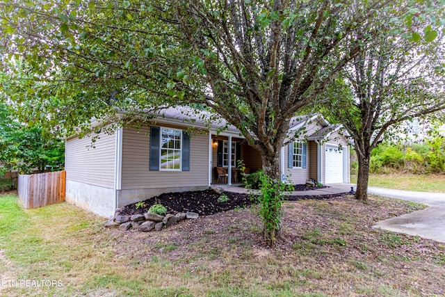 view of front of property featuring driveway, a front lawn, a porch, fence, and an attached garage