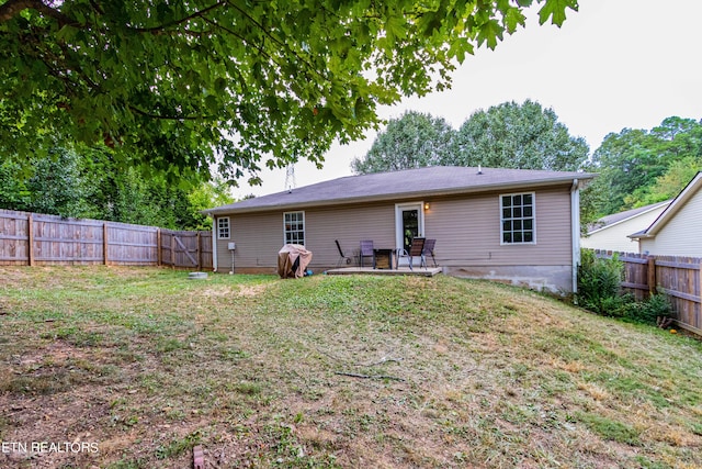 rear view of house with a patio, a fenced backyard, and a lawn