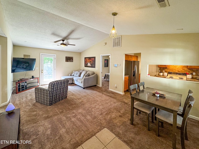 tiled living area featuring visible vents, lofted ceiling, a textured ceiling, and carpet flooring