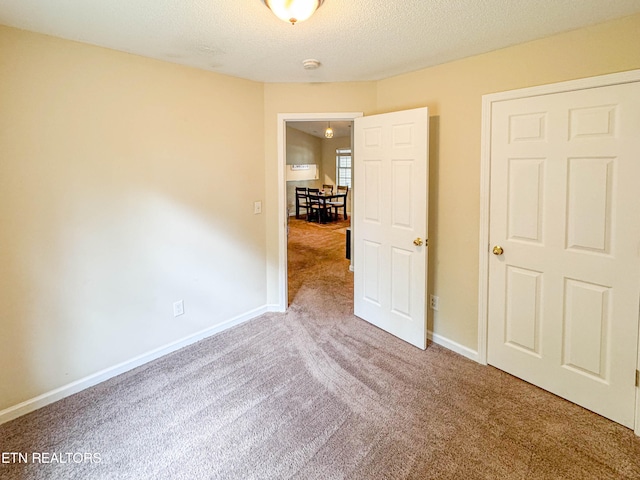 carpeted empty room with a textured ceiling and baseboards