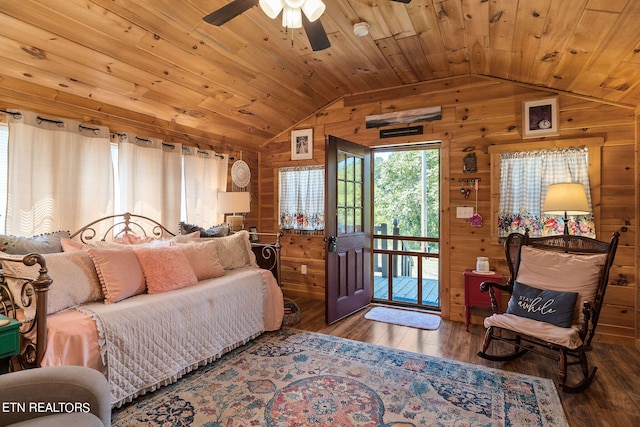 bedroom featuring wood walls, hardwood / wood-style floors, and vaulted ceiling