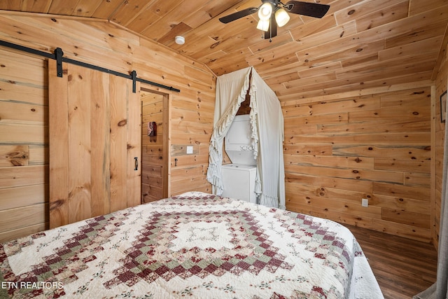 unfurnished bedroom featuring wooden walls, vaulted ceiling, a barn door, wood ceiling, and ceiling fan