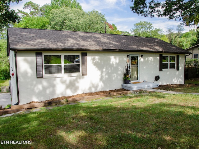 single story home with brick siding, a shingled roof, and a front yard