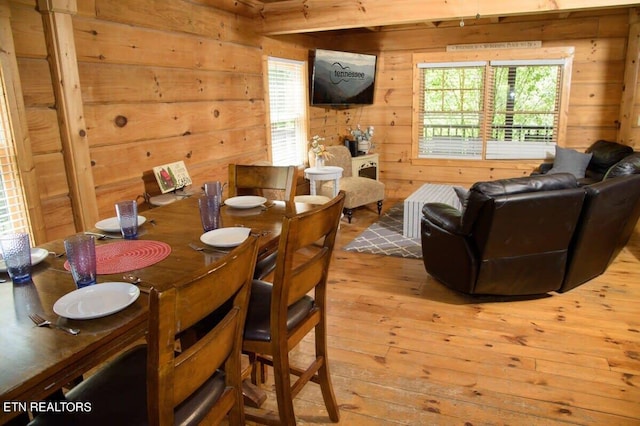 dining space with plenty of natural light, light wood-type flooring, and wooden walls