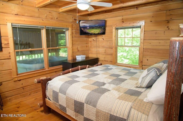 bedroom with hardwood / wood-style flooring, beam ceiling, and wooden walls