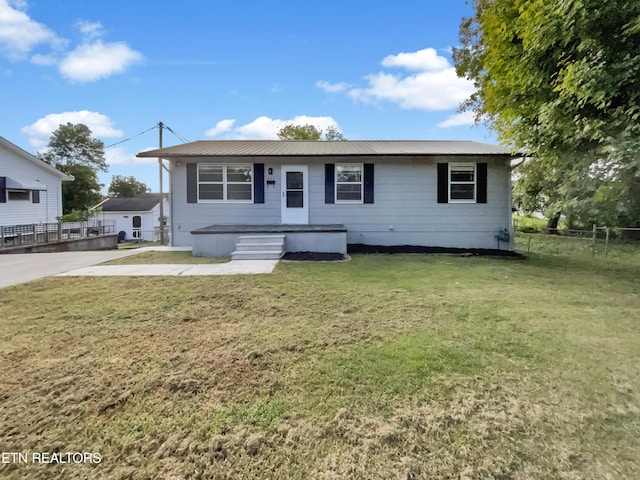 view of front of home featuring metal roof, a front lawn, and fence