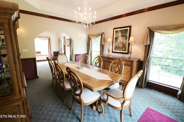 dining area featuring crown molding, carpet flooring, and a chandelier