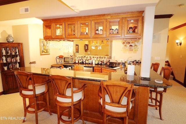 bar featuring light carpet, dark stone counters, stainless steel appliances, and sink