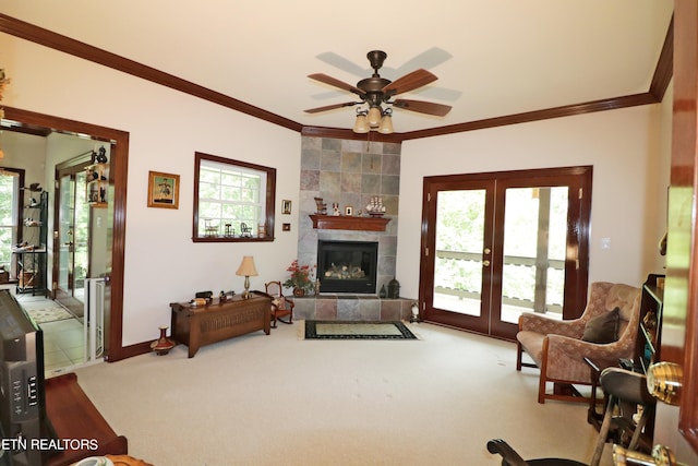 living room with carpet flooring, ceiling fan, a tiled fireplace, and a healthy amount of sunlight