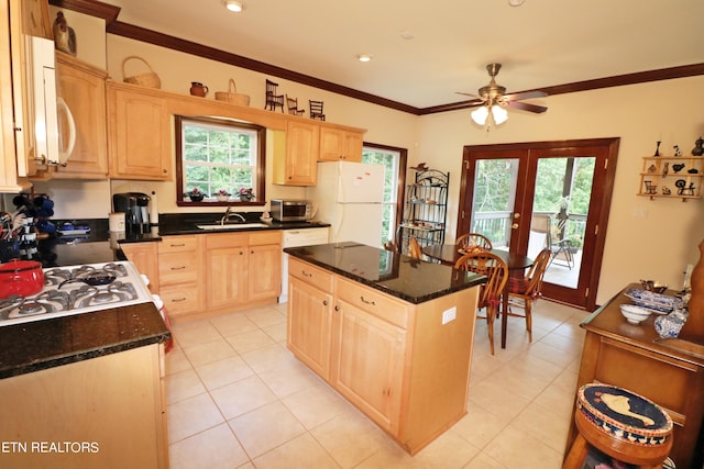 kitchen featuring white appliances, plenty of natural light, light brown cabinets, ceiling fan, and a kitchen island