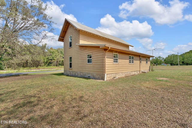 view of property exterior featuring metal roof, a yard, and crawl space