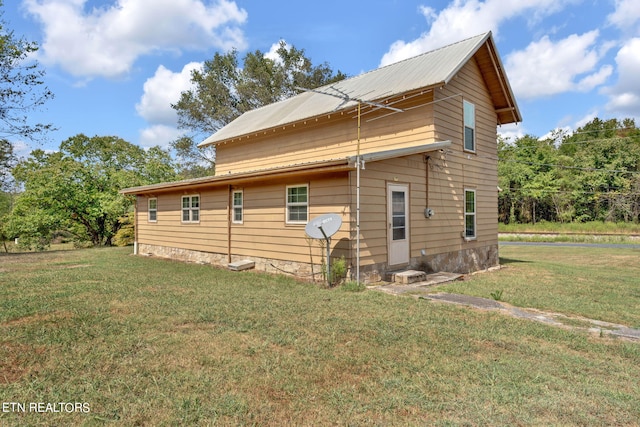 rear view of property featuring metal roof and a yard