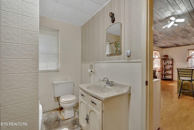 bathroom featuring toilet, wood ceiling, wood finished floors, vanity, and tile walls