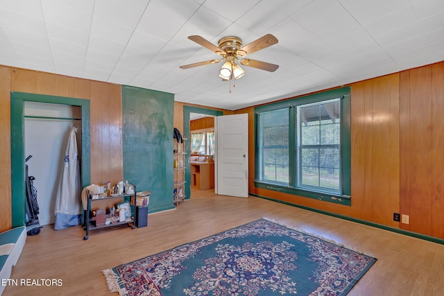 interior space with wood walls, ceiling fan, and wood finished floors