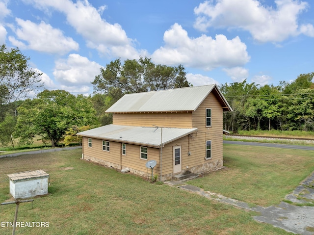 view of side of home featuring metal roof and a lawn