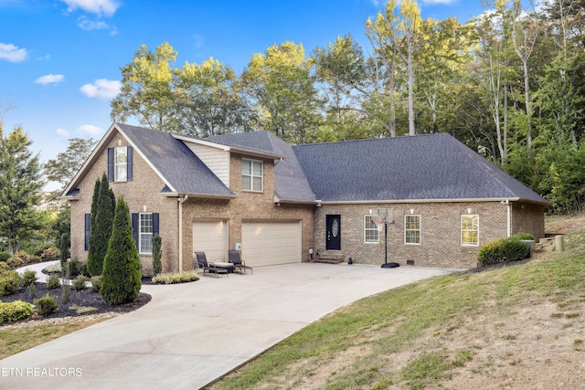traditional-style home with a garage, concrete driveway, brick siding, a front lawn, and a shingled roof