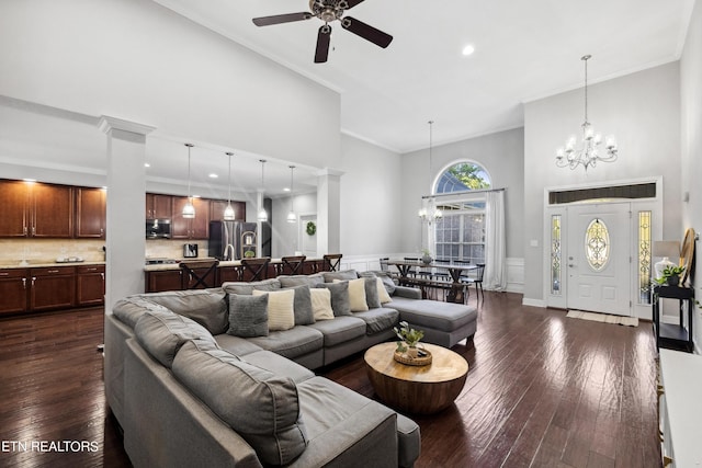 living room featuring dark wood-style flooring, a towering ceiling, and ceiling fan with notable chandelier