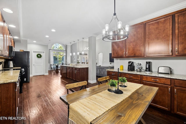 kitchen featuring dark wood-type flooring, a chandelier, hanging light fixtures, light stone countertops, and black appliances