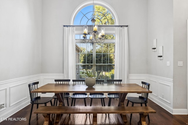 dining space with dark wood-style floors, a wealth of natural light, an inviting chandelier, and a wainscoted wall