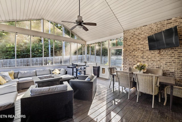 wooden terrace with a fenced backyard, an outdoor living space with a fire pit, grilling area, outdoor dining area, and a ceiling fan