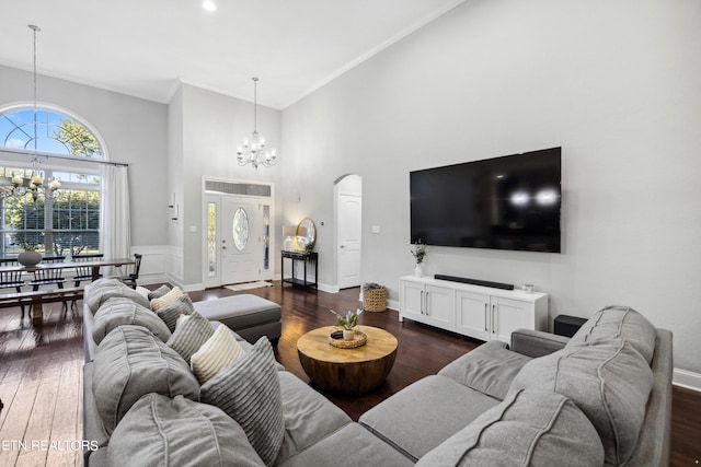 living area with baseboards, a notable chandelier, arched walkways, and dark wood-type flooring