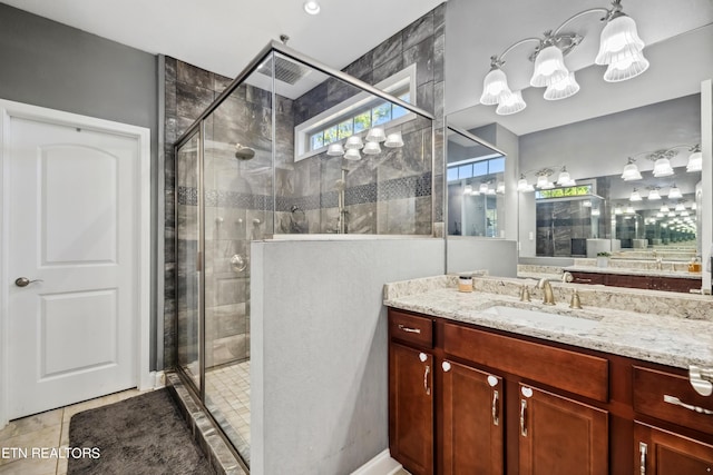 bathroom with tile patterned floors, vanity, a notable chandelier, and a shower stall