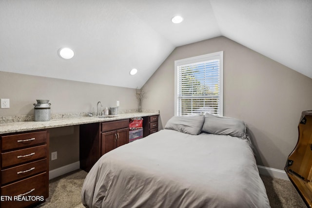 bedroom featuring vaulted ceiling, wet bar, baseboards, a sink, and light carpet