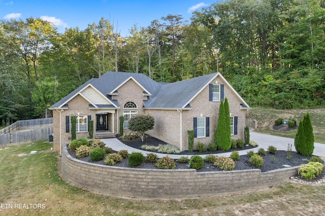 view of front of home with brick siding, fence, and a front lawn