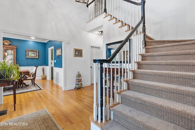 staircase featuring hardwood / wood-style floors, a towering ceiling, and ornamental molding