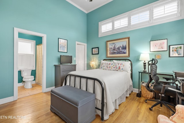 bedroom featuring light wood-type flooring, ensuite bath, and multiple windows