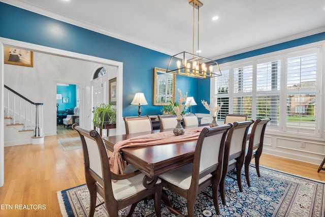 dining area with a chandelier, light wood-type flooring, and crown molding