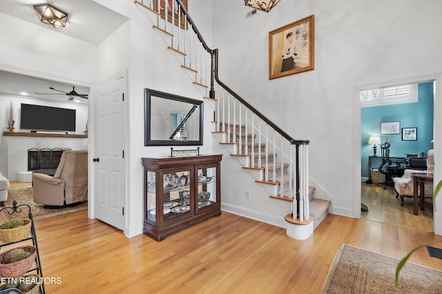 stairs featuring a high ceiling, hardwood / wood-style flooring, and ceiling fan