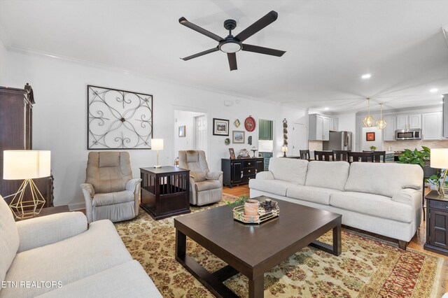 living room with ceiling fan, light hardwood / wood-style floors, and ornamental molding