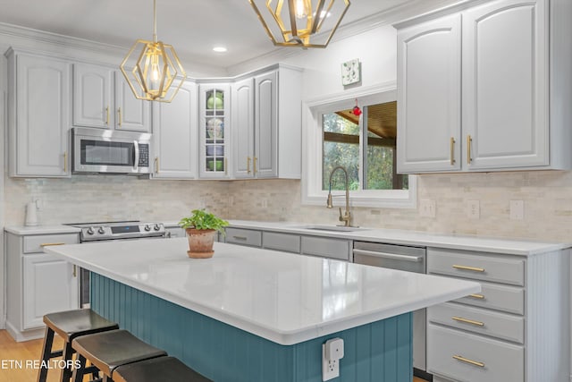 kitchen featuring a kitchen bar, stainless steel appliances, crown molding, decorative light fixtures, and a kitchen island