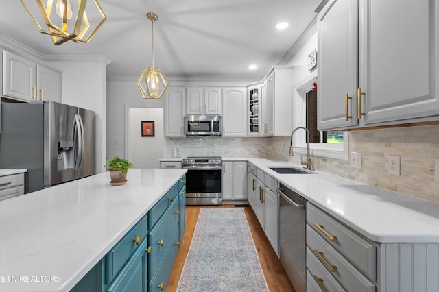 kitchen featuring blue cabinetry, sink, hanging light fixtures, light hardwood / wood-style floors, and appliances with stainless steel finishes