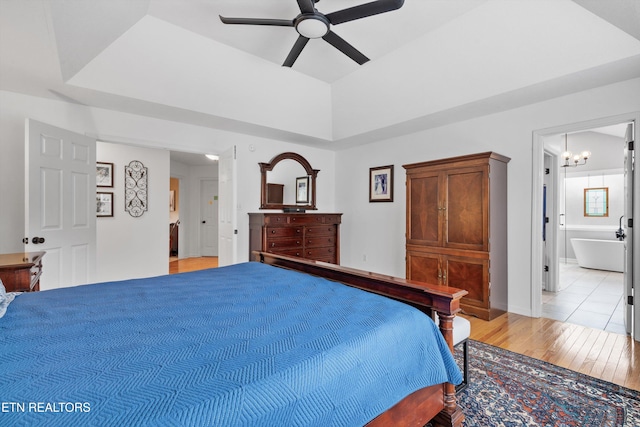 bedroom with ensuite bath, ceiling fan with notable chandelier, and light wood-type flooring