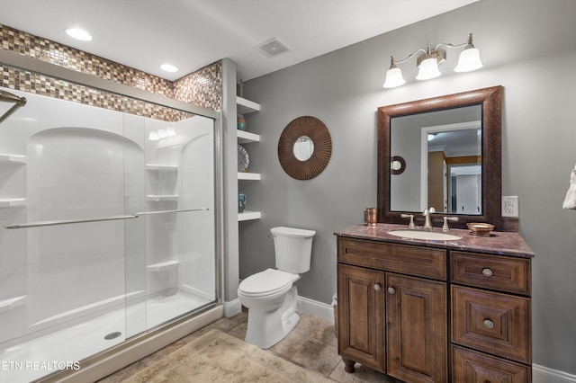 bathroom featuring toilet, vanity, tile patterned floors, and a shower with door