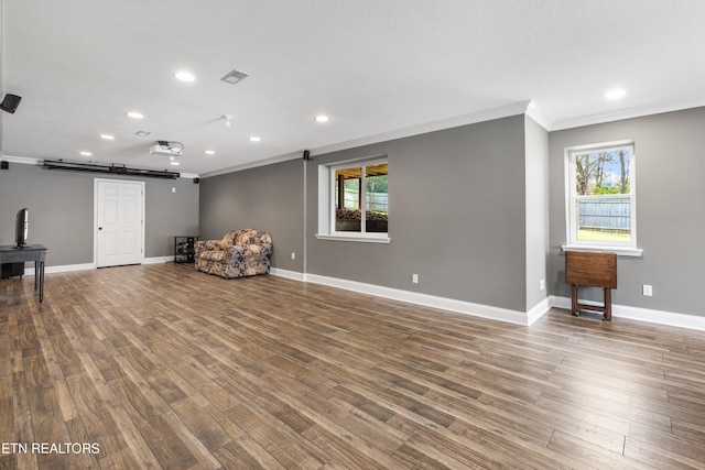 unfurnished room featuring hardwood / wood-style floors, plenty of natural light, a barn door, and ornamental molding