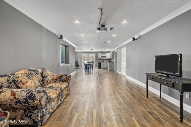 living room featuring wood-type flooring, a textured ceiling, ceiling fan, and ornamental molding