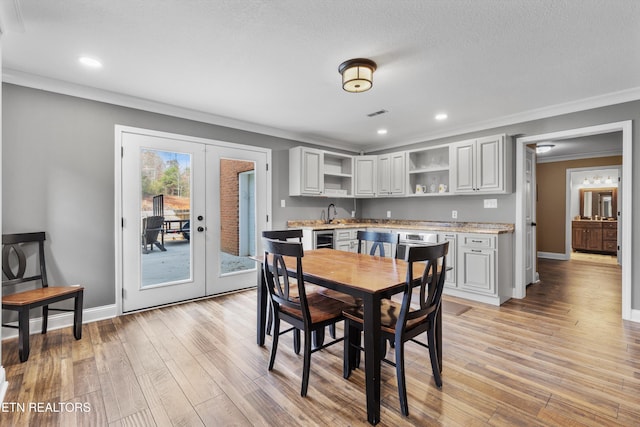 dining room with french doors, crown molding, a textured ceiling, light hardwood / wood-style floors, and beverage cooler