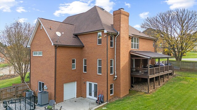 back of property with a garage, central AC unit, and a lawn